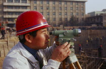 Surveyor using a theodolite working on a building construction site.