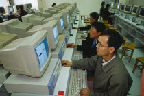 Internet Cafe with men seated at rows of computers.