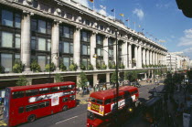 Selfridge s store exterior with red double decker buses going past on the road in the foreground.Oxford Street