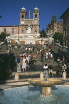 Piazza di Spagna.  Fountain in the foreground with people on the Spanish Steps behind.