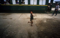 Young boy running along platform of railway station in front of stationary carriage