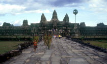 View along wide stone path towards temples and visitors  small girl and temple guards in the foreground.