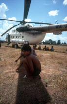 Young boys crouching in the shade cast by the blades of a UN helicopter.