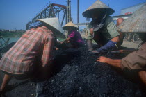 Coal ladies crouched on piles of coal wearing traditional conical hats.