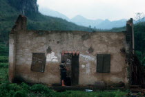 Women holding a child  standing in the doorway of the ruined house in which they are living.  China in the distance.