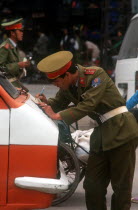 Policeman leaning on the bonnet of a truck to write out a traffic ticket.