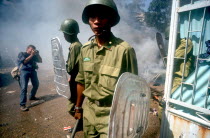 Anti Khmer Rouge demonstration outside their city headquarters.  Soldiers with riot shields and press photographer.