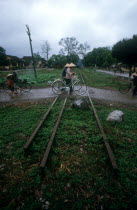 People with bicycles crossing a disused railtrack near the Chinese border.