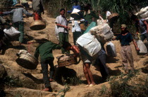 Smuggling on the border with China.  Porters carrying baskets of goods up a steep hillside.