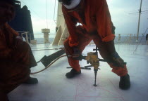 Man using a power drill on board a ship in  Indonesia.