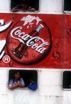 Advertisment for Coca Cola on the side of a ferry  passengers at the windows above and below it.