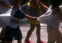 Group of young children  holding on to each other s clothing to form a line.