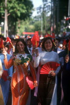 Young women holding flags and fans on the 25th Anniversary Parade for the liberation of Saigon.