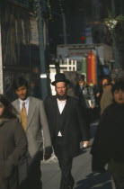 Orthodox Jewish man walking among other people on 47th Street.