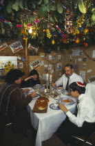 England.  Jewish family eating a meal in a Sukka during the Sukkot Festival.