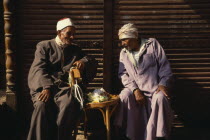 Two old Muslim men seated  in conversation.