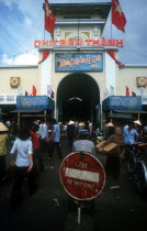 Main entrance to Ben Thanh Market  part view of belfry and clock  crowds of people.