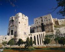 The Citadel.  Exterior of stone fortification and arched viaduct between towers  Halab