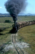 Train transporting sugar cane with plumes of black smoke pouring from the engine