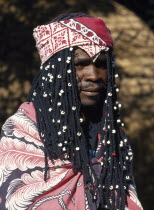 Venda Tribesman with long plaited hair decorated with white beads and head scarf.