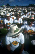 Crowd of seated men and women wearing matching hats and T-shirts for the July 26th celebrations
