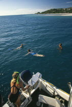 Tourists snorkelling from dive boat.