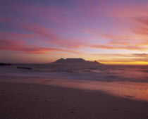 View of Table Mountain at dusk taken from Bloubergstrand shore line dramatic sky.
