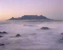 View of Table Mountain at dawn taken from Bloubergstrand shore line with heavy mist.