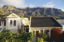 Houses and gardens in the foreground and Table Mountain and Table Cloth mist in background.
