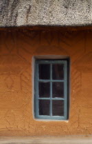 Detail of typical house with green framed window in recess and orange walls.