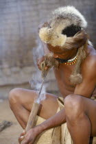Zulu man burning hole into shaft to make spear.