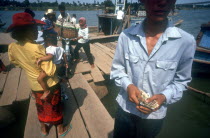 Tonle Sap ferry.  Man taking money in foreground  passengers boarding and disembarking.
