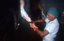 Abattoir with man skinning hanging carcase