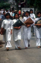 Line of young female students in traditional white dress.