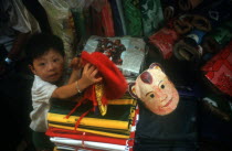 Central Market.  Small boy in shop selling fabric and flags. Coloured mask beside him.