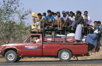 Overcrowded country minibus with people on the roof and hanging of the back BurmaMyanmar Pagan
