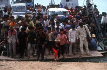 Crowds of people and vehicles disembarking from the Mekong ferry.