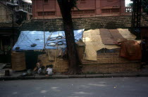 Vietnam, Hanoi, Slum housing by roadside with group of children at entrance.