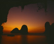 Phra Nang beach  orange sunset behind rock formations in the sea