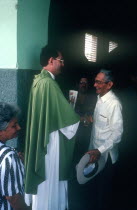 Priest shaking the hand of one of his worshipers exiting the church