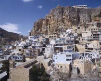 Blue & white square houses built under & into rock face  churches