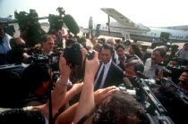 Press surrounding the arrival of Son Sen on airport runway.