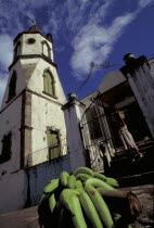 The Methodist Church with Harvest Festival Offering of bananas on the pavement as woman leaves the church