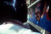 View from the back of a motorbike over the helmet of the driver and along the side of a bus in a traffic jam