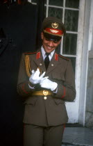 Man in military uniform putting on white gloves