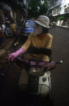 Woman on moped wearing a scarf over her nose and mouth to protect against the smog