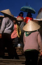 Women at Dalat market with wide straw hats and umbrella.