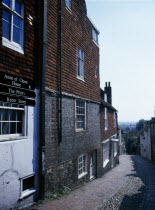 View down cobbled old street with cottage housing and a street sign showing directions towards the Ann of Cleves House and Priory