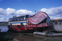 Colourful houseboat fabricated with various bus and car parts moored on the river Adur.