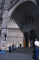 Kensington. Natural History Museum. Exterior view  with visitors walking up the steps to the main entrance.